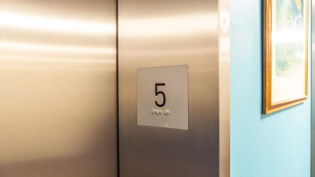 A lift call panel with a large floor number and braille beneath it