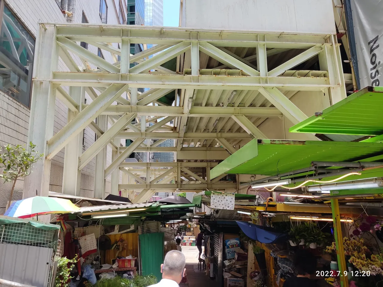 Canopies and steel frames turn the lane into a covered hall.
