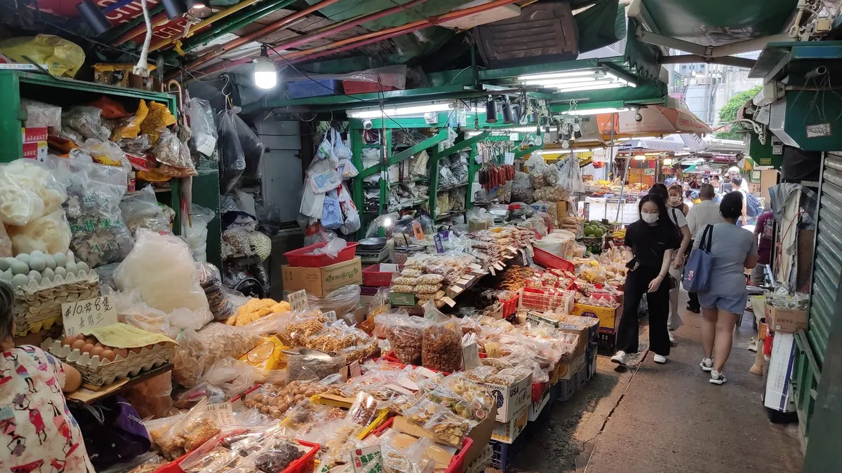 Graham Street market stalls under green canopies, crates of dried goods in the foreground