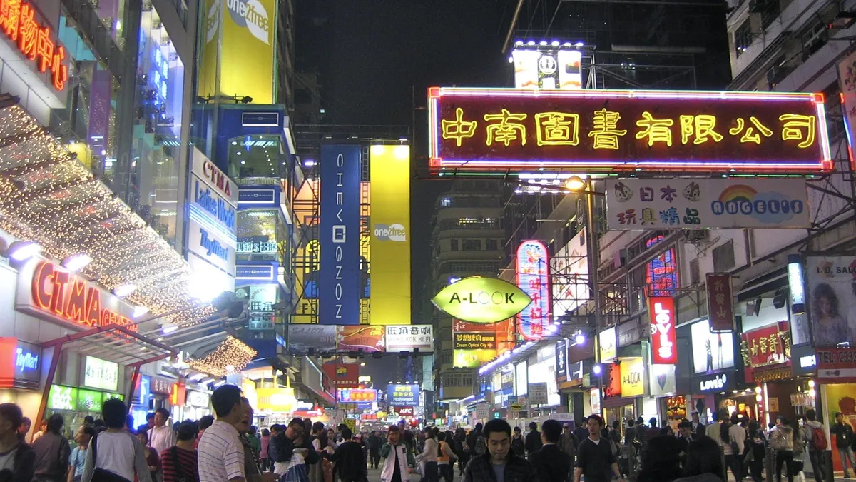 A crowded shopping street at night under dozens of neon and LED signs