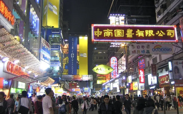 A crowded shopping street at night under dozens of neon and LED signs