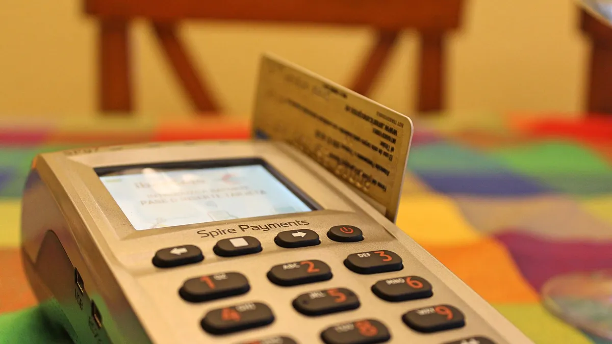 A bank card inserted into a handheld payment terminal