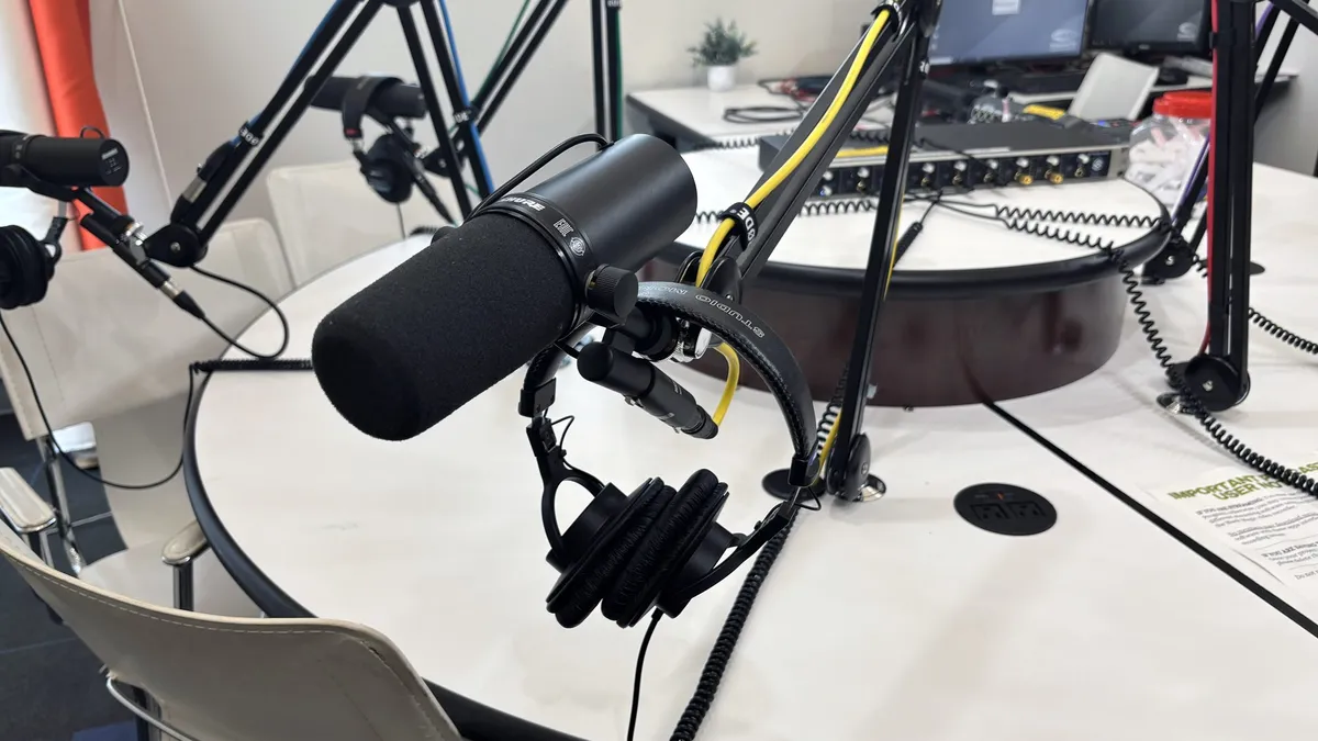Broadcast microphones on boom arms around a round studio table