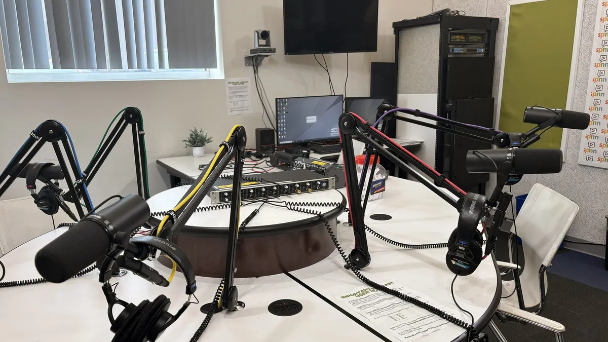 A podcast studio with microphones on boom arms around a round table
