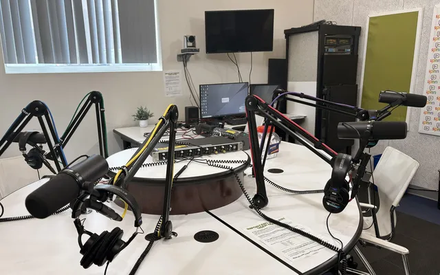A podcast studio with microphones on boom arms around a round table