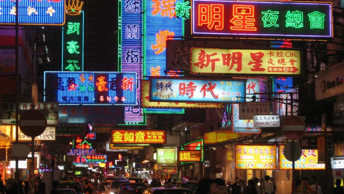 Stacked neon signs in Chinese and English over a busy street at night