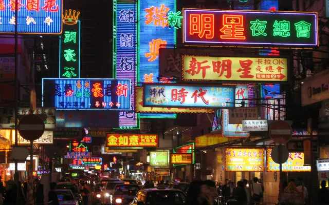 Stacked neon signs in Chinese and English over a busy street at night